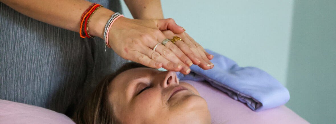 Sophie from Be About Health placing her hands above a client during a Reiki healing session in Somerset.